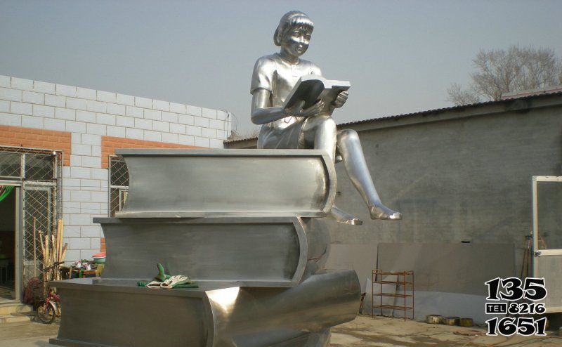 读书雕塑-景区玻璃钢女孩坐着书本上的读书雕塑高清图片