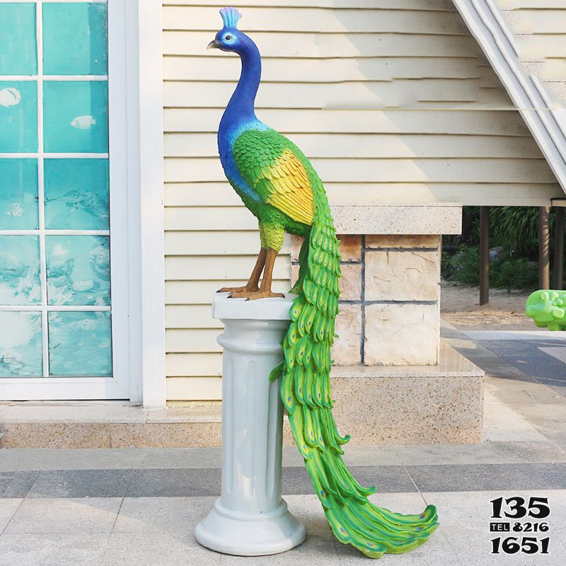 孔雀雕塑-花园里一只立在石柱上的玻璃钢彩绘孔雀雕塑高清图片