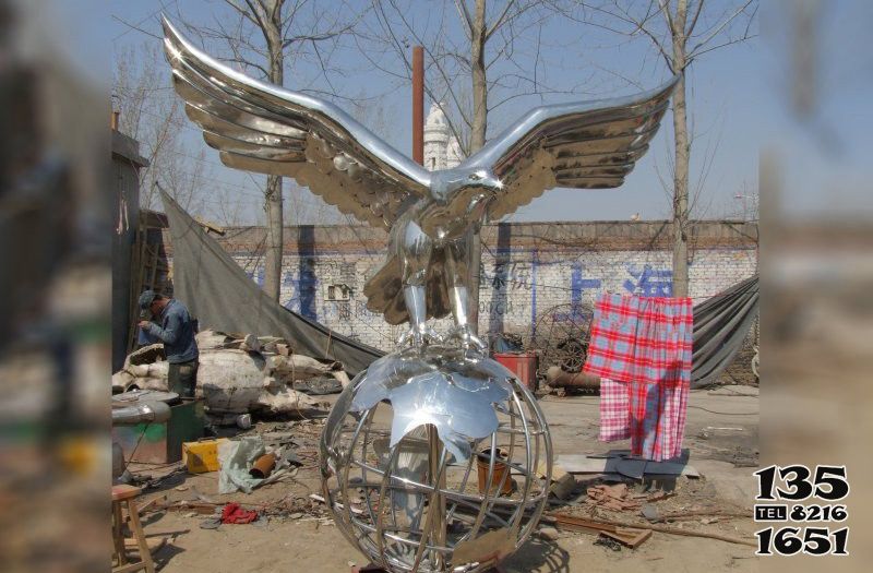 老鹰雕塑-农场一只球上休息的不锈钢老鹰雕塑高清图片