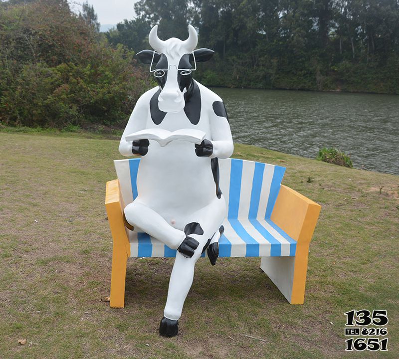 牛雕塑-公园一只看书奶牛坐靠椅玻璃钢牛雕塑高清图片