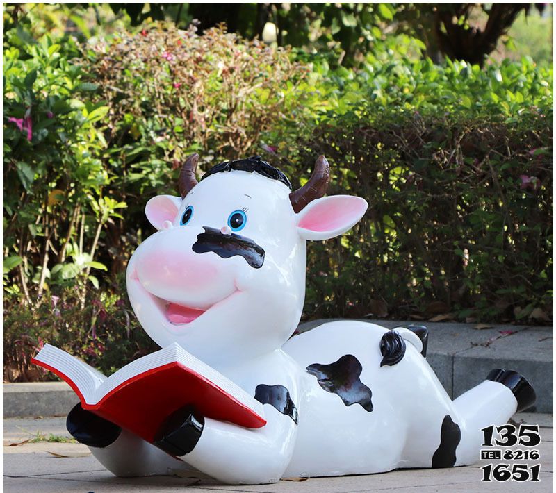 牛雕塑-图书馆一只趴着看书的卡通玻璃钢牛雕塑高清图片