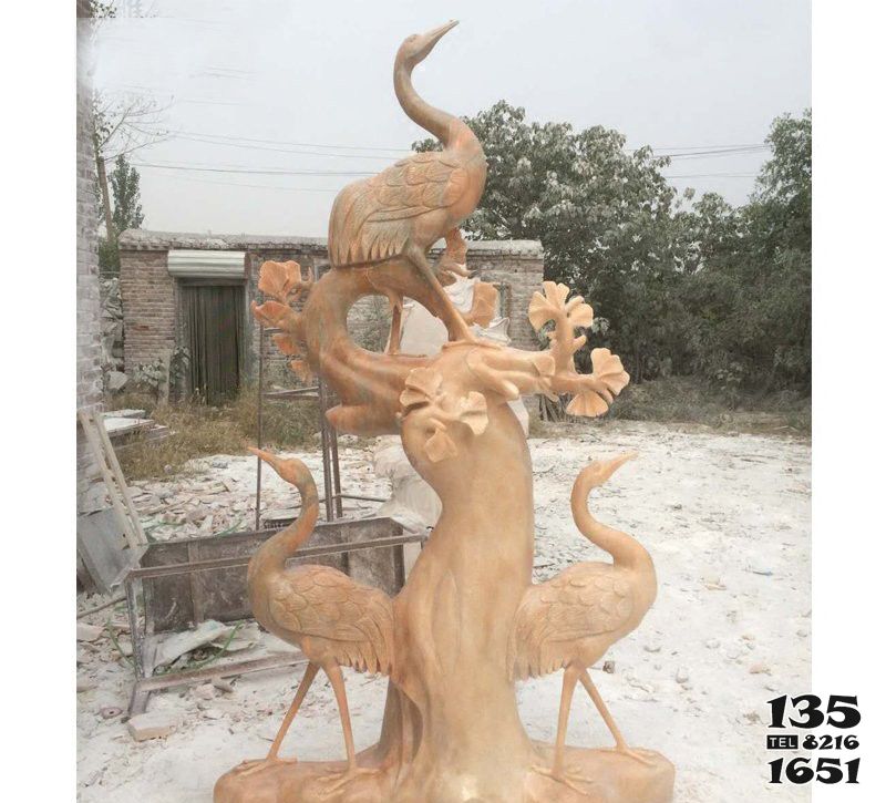 仙鹤雕塑-公园晚霞红石雕创意树上站着的仙鹤雕塑高清图片